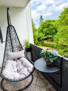 eine Schaukel auf einem Balkon mit einem Tisch und Blumen in der Unterkunft Messewohnung für 5 Gäste mit Balkon und Lift in Hannover