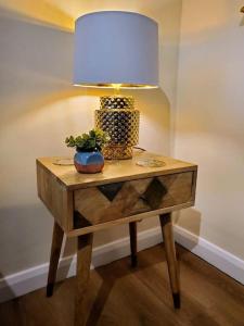 a table with a lamp and a plant on it at Court Cottage, 2 bed period house in Sarre