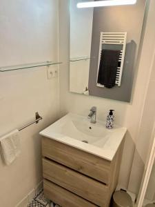 La salle de bains est pourvue d'un lavabo et d'un miroir. dans l'établissement Appartement meublé et rénové centre-ville Saint-Nazaire, à Saint-Nazaire