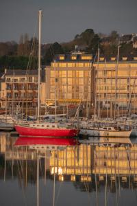 un bote rojo sentado en el agua junto a los edificios en Le Nautica Hôtel, en Perros-Guirec