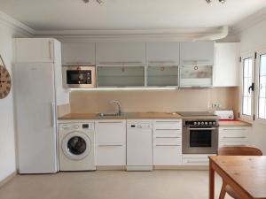 a kitchen with white cabinets and a washer and dryer at Dunas de Famara in Famara
