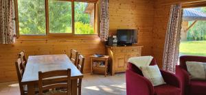 ein Esszimmer mit einem Tisch, Stühlen und einem TV in der Unterkunft RHODOS, Confort et Espace in Ovronnaz