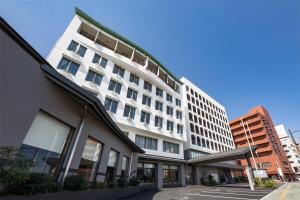 a large white building with windows on a street at Hotel New Tsuruta in Beppu