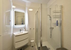 a white bathroom with a shower and a sink at Apartman Badi in Dugopolje +16 photos