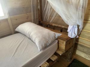 ein Bett mit einem weißen Kissen auf einer hölzernen Plattform in der Unterkunft Coconuts Bandas in Jambiani