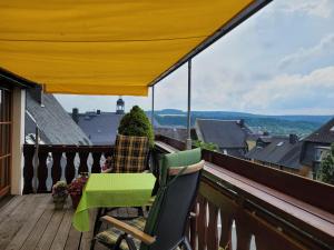 un balcón con 2 sillas y un dosel amarillo en Ferienwohnungen Stephan, en Marienberg