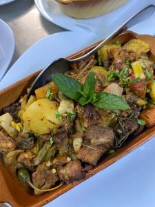 a bowl of food with meat and vegetables with a spoon at Hotel Neda Galichnik in Galičnik