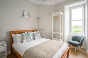 a bedroom with a bed and a chair and a window at 2BR New Town Castle View Apartment in Edinburgh