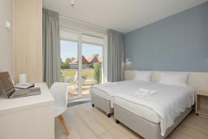 a bedroom with a bed and a desk with a laptop at BURSZTYN - BERNSTEIN APARTMENTS in Dąbki