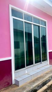 ein rosafarbenes Gebäude mit einem Fenster auf der Seite in der Unterkunft Nazla Homestay Pendang 2 in Pendang