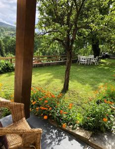 une terrasse avec une table, un arbre et des fleurs dans l'établissement Casa adosada con gran jardín en Osséja, à Osséja