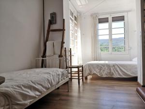 - une chambre blanche avec 2 lits et une fenêtre dans l'établissement Casa adosada con gran jardín en Osséja, à Osséja