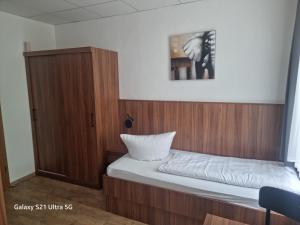 Dormitorio pequeño con cama y armario de madera en 1A Hotel Zimmer frei, en Spremberg
