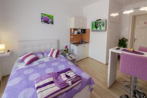 a bedroom with a purple bed and a kitchen at Apartments Trend in Rijeka