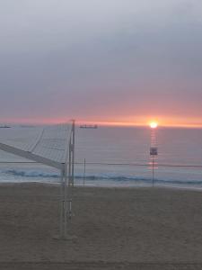 een bankje op het strand met de zonsondergang op de achtergrond bij studio by the sea in Ashdod