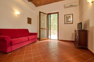 a living room with a red couch and a television at Antichi Palmenti - Erica in San Vincenzo