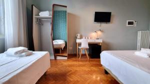 a room with two beds and a desk and a mirror at Locanda Al Volo Tor Bandena in Trieste