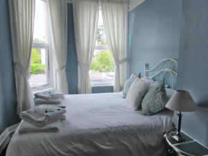 a blue bedroom with a bed with towels on it at Birchwood House in Paignton