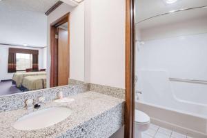 a bathroom with a sink and a toilet and a mirror at Days Inn by Wyndham Monett in Monett