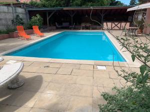 ein blauer Pool mit orangefarbenen Stühlen und einem Tisch in der Unterkunft GITE CENTRE ALSACE in Barr