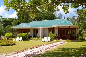 a house with a green roof and white chairs at Les Villas D'or in Baie Sainte Anne