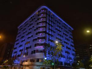 un edificio de hotel se ilumina por la noche en Mercure Alameda Quito en Quito