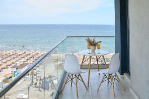 een balkon met een tafel en stoelen en de oceaan bij Paradise Sea View 2BD apt Spa n Pools beach resort in Mamaia Nord – Năvodari