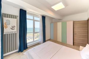 een slaapkamer met een bed en een groot raam bij Paradise Sea View 2BD apt Spa n Pools beach resort in Mamaia Nord – Năvodari