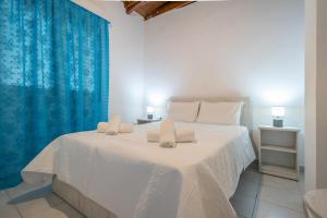 sypialnia z dużym białym łóżkiem z niebieskimi zasłonami w obiekcie Castle View Apartments w mieście Myrina