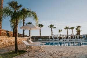 una piscina con sillas, sombrilla y palmeras en La Restuccia - Masseria Urban, en Lequile