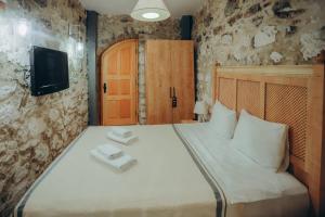 um quarto com uma cama branca e uma televisão na parede em 1881 HALİL EFENDİ OTEL em Alacati