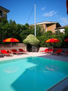 una piscina con sombrillas y sillas rojas en Il Sogno Apartments, en Desenzano del Garda