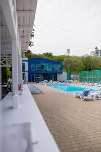 a swimming pool with lounge chairs and a building at Black Sea Hotel Otrada in Odesa