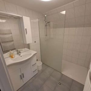 baño blanco con ducha y lavamanos en Pension Steinadler Garden and private parking en Murau