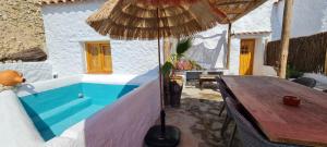 a wooden table with an umbrella on a patio at Cuevas Los Coloraos - La Cuadra in Villanueva de las Torres