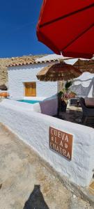 a sign for a restaurant with an umbrella and a building at Cuevas Los Coloraos - La Cuadra in Villanueva de las Torres