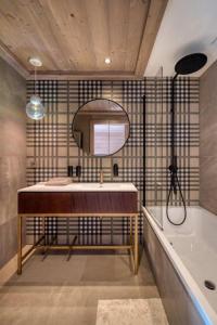 a bathroom with a sink and a tub and a mirror at Rochebrune - Appartement de luxe in Megève