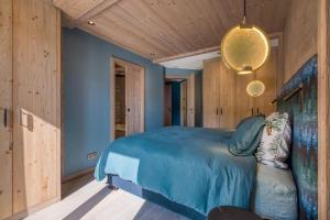 a bedroom with a blue bed and wooden walls at Rochebrune - Appartement de luxe in Megève