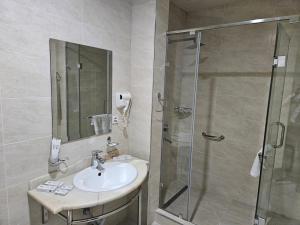 W łazience znajduje się umywalka i przeszklony prysznic. w obiekcie Silk Road Kokand Hotel w mieście Kokand