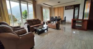 a living room with couches and chairs and a table at Velus Bungalow Ooty in Ooty