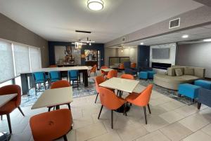 - une salle d'attente avec des tables, des chaises et un canapé dans l'établissement La Quinta Inn & Suites by Wyndham Fayetteville I-95, à Fayetteville