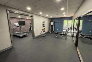 una palestra con sala fitness dotata di macchinari e specchio di La Quinta Inn & Suites by Wyndham Fayetteville I-95 a Fayetteville