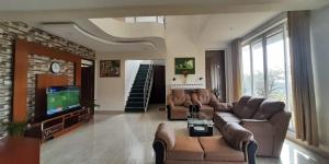 a large living room with couches and a tv at Velus Bungalow Ooty in Ooty +29 photos