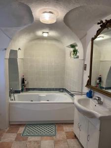 La salle de bains est pourvue d'une grande baignoire blanche et d'un lavabo. dans l'établissement The Prince of the Old Town Masserano, à Masserano