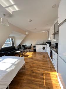 a kitchen and living room with a couch and a table at RC Airport Rooms in Stanwell