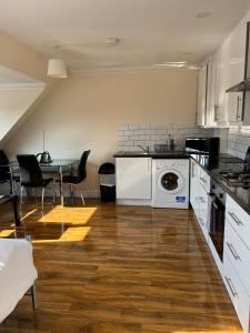 a kitchen with a washer and dryer and a table at RC Airport Rooms in Stanwell