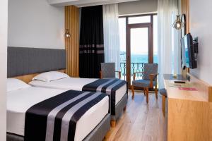 チャナッカレにあるBuyuk Truva Hotelのベッド2台とバルコニーが備わるホテルルームです。