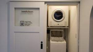 una lavadora y secadora en una habitación junto a una puerta en Hichu House ハイチューハウス, en Nago