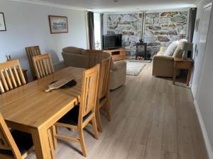 a dining room and living room with a table and chairs at Newhall Cottage in Bressay