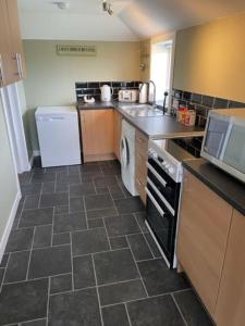 a kitchen with a washer and a dishwasher and a sink at Newhall Cottage in Bressay